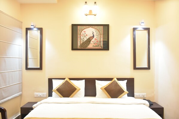 Une chambre d’hôtel avec un lit, deux tables de chevet, un miroir et une œuvre d’art encadrée accrochée au mur.