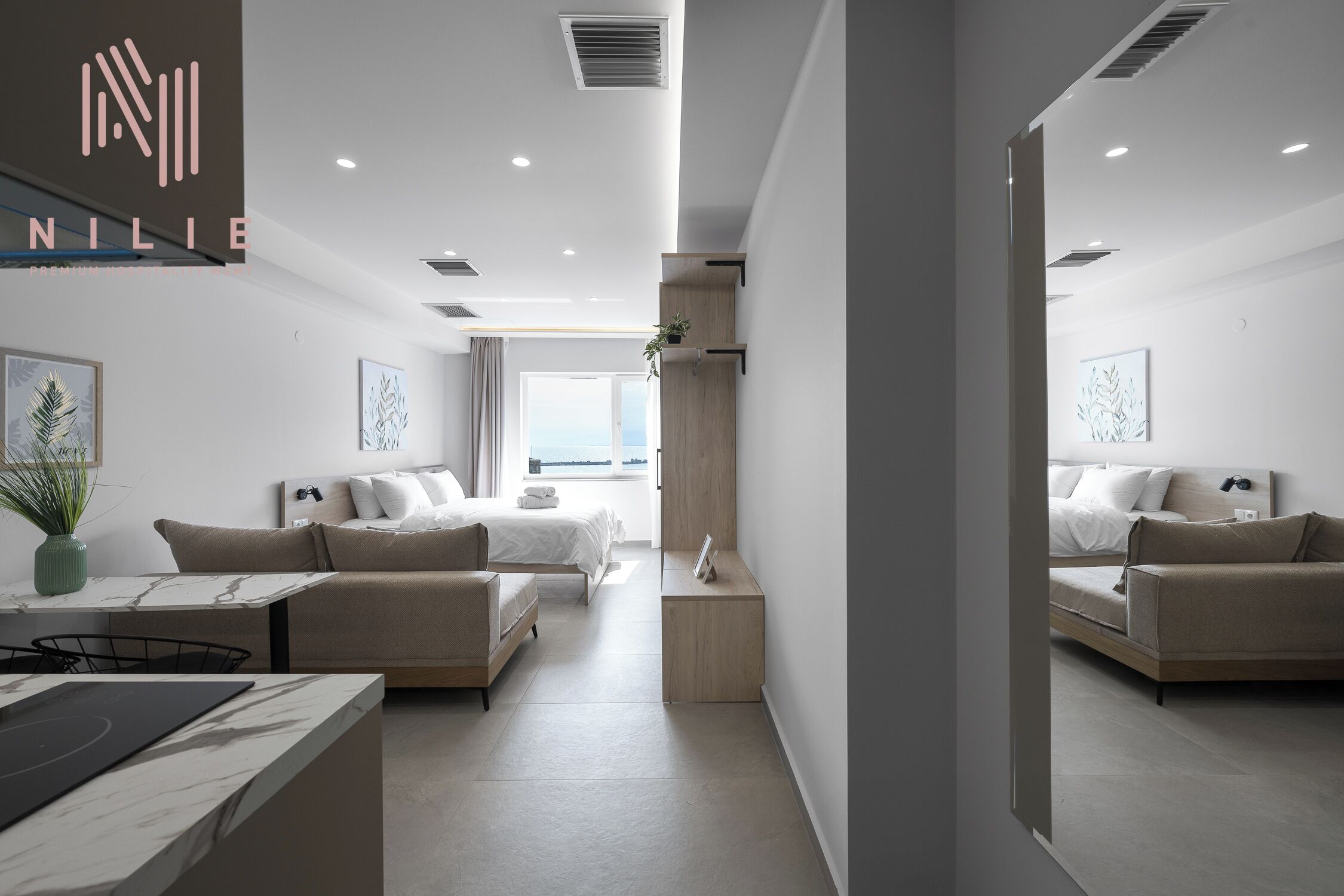 Una habitación de hotel moderna con cama, sofá, escritorio y espejo.