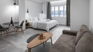 Una habitación de hotel moderna con una cama, un sofá, una mesita y un escritorio.