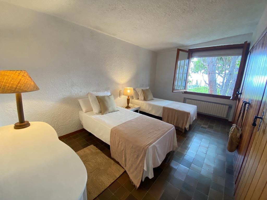 A room with two beds, a lamp, a window, and a radiator.
