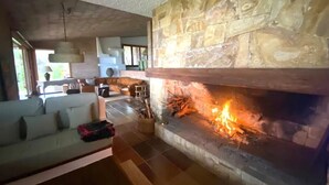 A living room with a stone fireplace, a sofa, and a hanging light fixture.