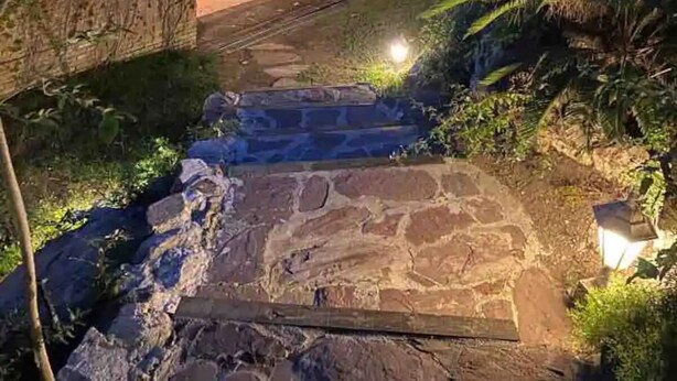 A stone staircase leading to a brick building with a bench and a large pot.