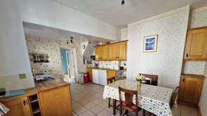 A kitchen with wooden cabinets, a dining table with a patterned tablecloth, and a small island with a sink.