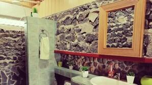 A bathroom with a stone wall, a wooden vanity, a white sink, and a toilet. - Villa Bonilla 12P 3C 2N (Provincia de Cartago)