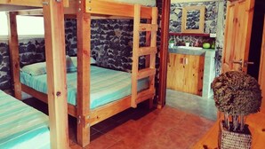 A rustic cabin with bunk beds, a stone wall, a wooden kitchen, and a small dining area. - Villa Bonilla 12P 3C 2N (Provincia de Cartago)