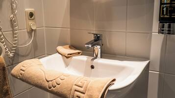 A bathroom with a white sink, a towel, and a hand wash dispenser.