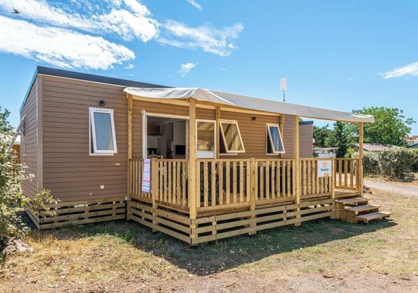 A wooden mobile home with a porch, a covered outdoor area, and a small deck. - Camping Lanterna - Eurocamp (Tar)
