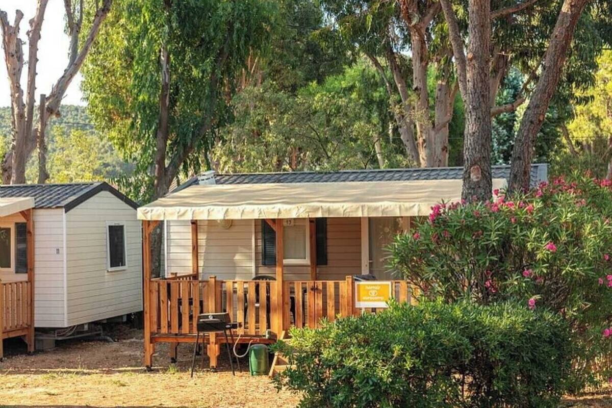 A mobile home with a porch, a small table, and a chair.