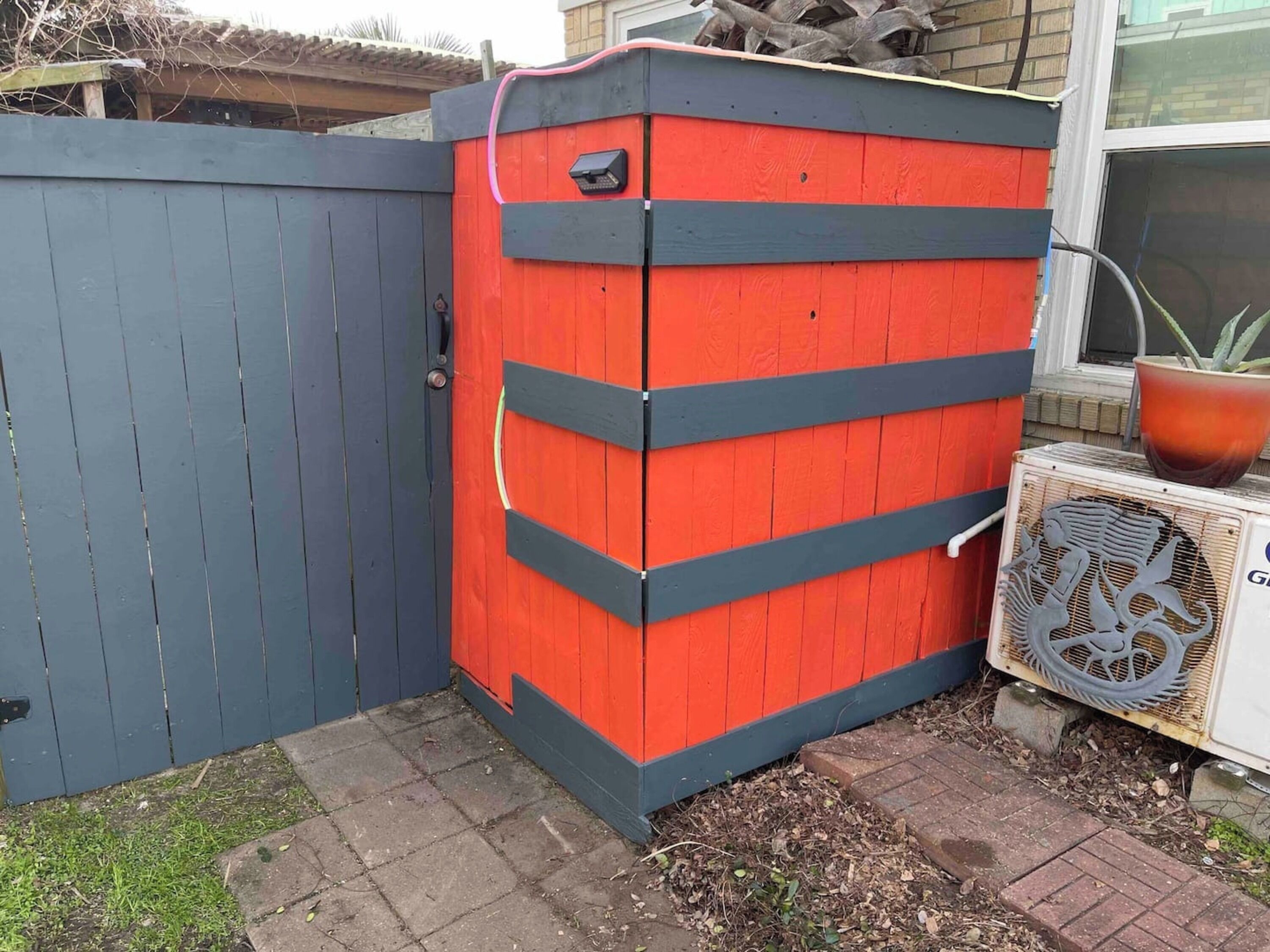 A wooden shed with a red and black exterior, a door, and a small window.