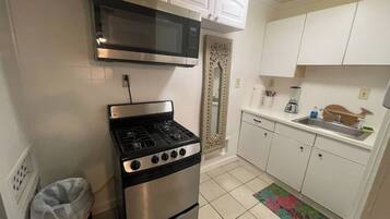 A kitchen with a stove, microwave, and white cabinets.
