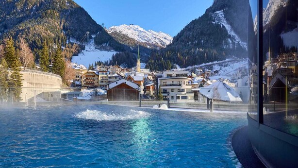 A swimming pool with a view of a mountain town, including buildings and a church.