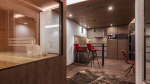 A modern kitchen with wooden cabinets, a dining area with red chairs, and a large mirror.