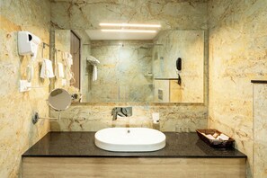 Een aparte badkuip en douche, een haardroger, pantoffels, handdoeken