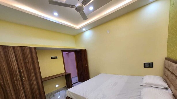 A bedroom with a bed, wooden wardrobe, and a ceiling fan. - Relax (Bhatkal)
