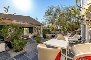 A patio area with outdoor seating, potted plants, and a building with a green door. - Artsy 4BR DIP Villa w Community Pool Gym (Dubai)
