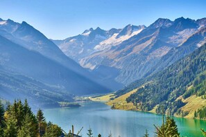 Un paysage montagneux avec un lac, entouré de forêts denses et dominé par un ciel dégagé.