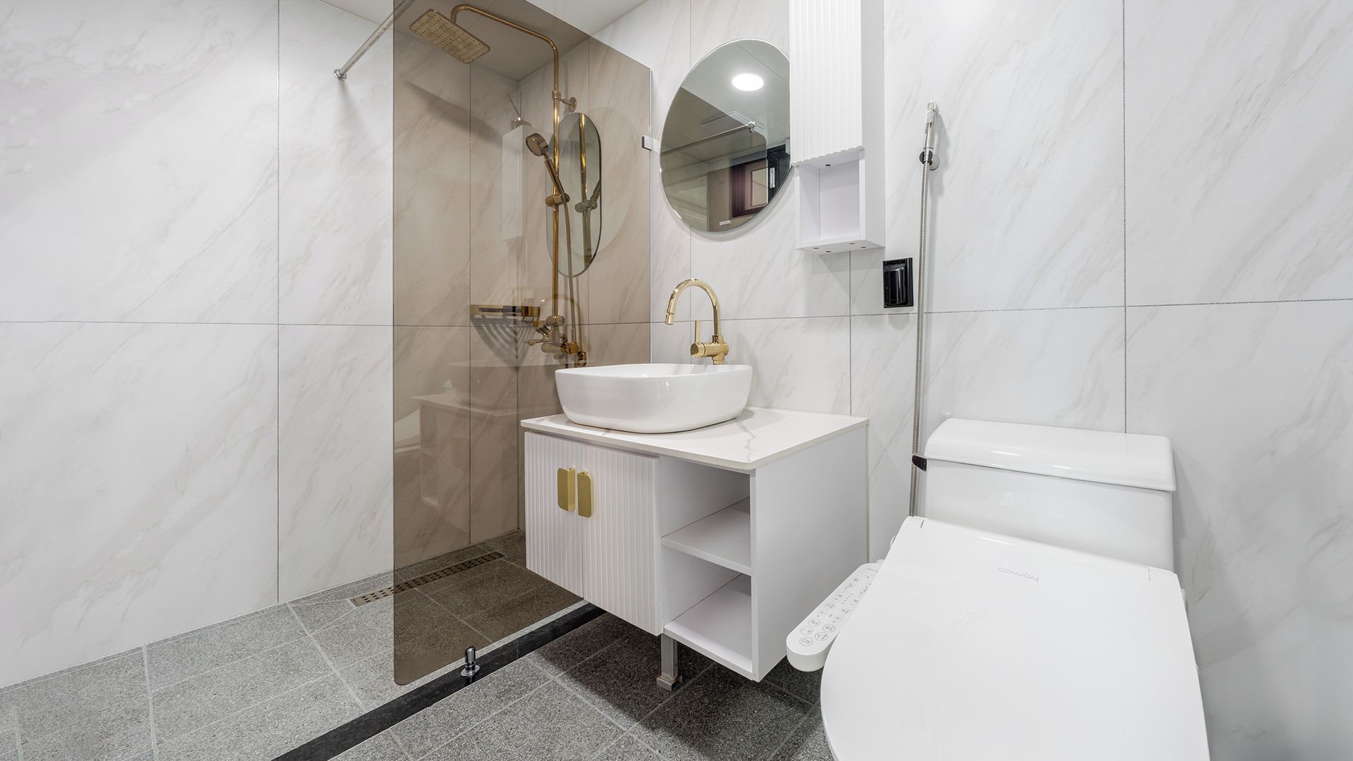 Un baño moderno con un lavabo blanco, detalles dorados y una ducha con cerramiento de vidrio.