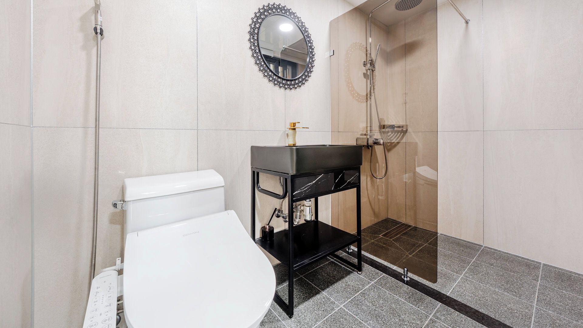 A modern bathroom with a toilet, a black sink with a mirror above it, and a shower area.