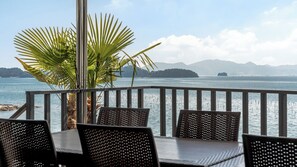 An outdoor seating area with a view of a calm body of water and distant mountains. - Sacheon Ara Private Pool Villa (Sacheon)