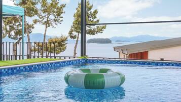 Una piscina con vistas al mar y a las montañas, rodeada de árboles y un edificio.