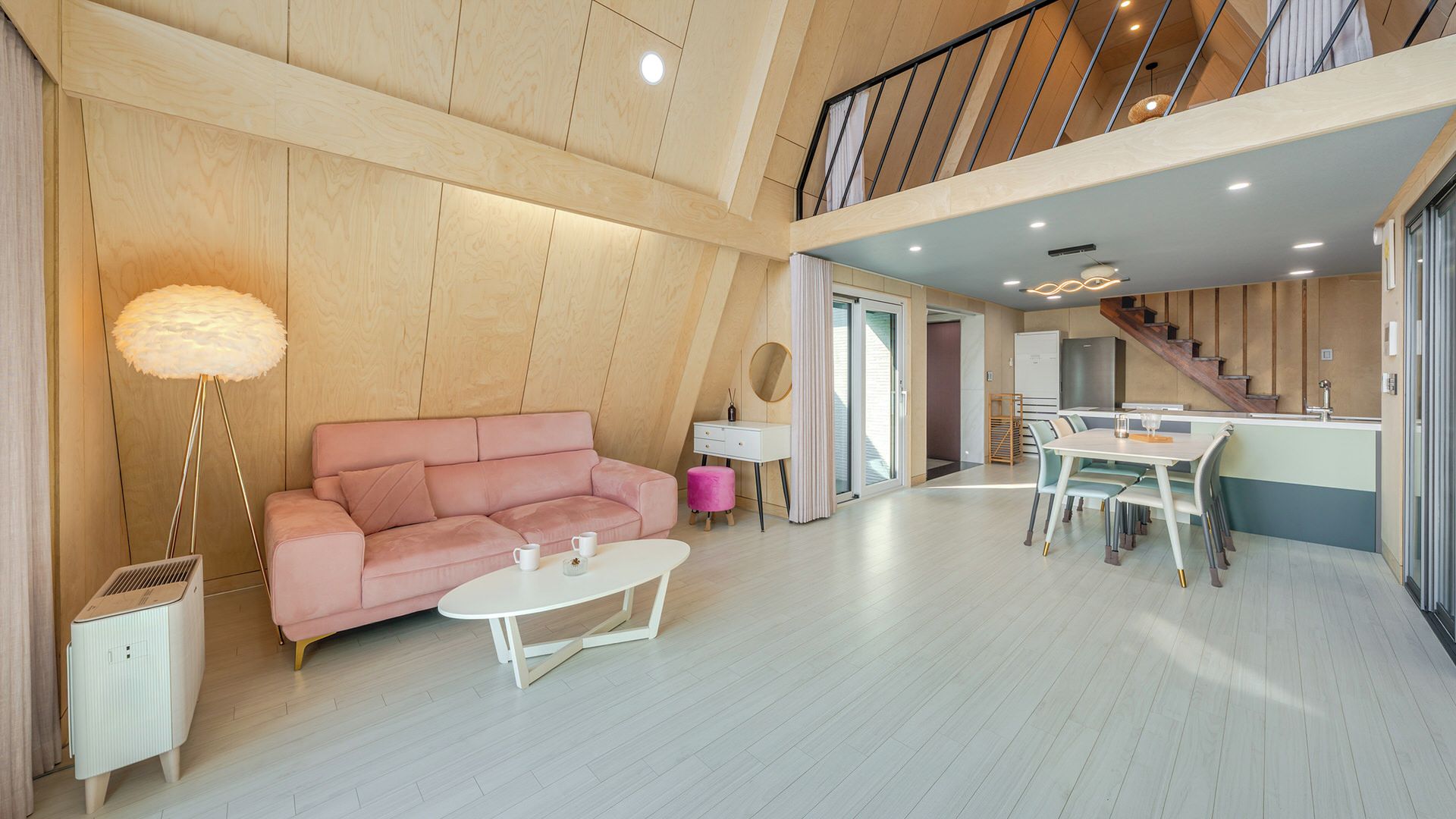 A modern living room with a pink sofa, a white coffee table, and a dining area with a table and chairs.