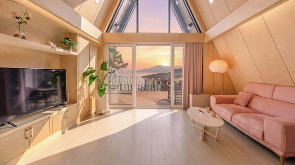 A modern living room with a television, sofa, coffee table, and potted plants. - Sacheon Ara Private Pool Villa (Sacheon)