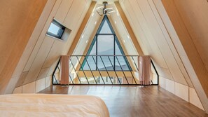 A high-ceilinged room with a sloped ceiling, a bed, a small window, and a view of the outdoors. - Sacheon Ara Private Pool Villa (Sacheon)