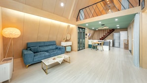A modern living room with a blue sofa, a white coffee table, and a dining area with a small table and chairs. - Sacheon Ara Private Pool Villa (Sacheon)