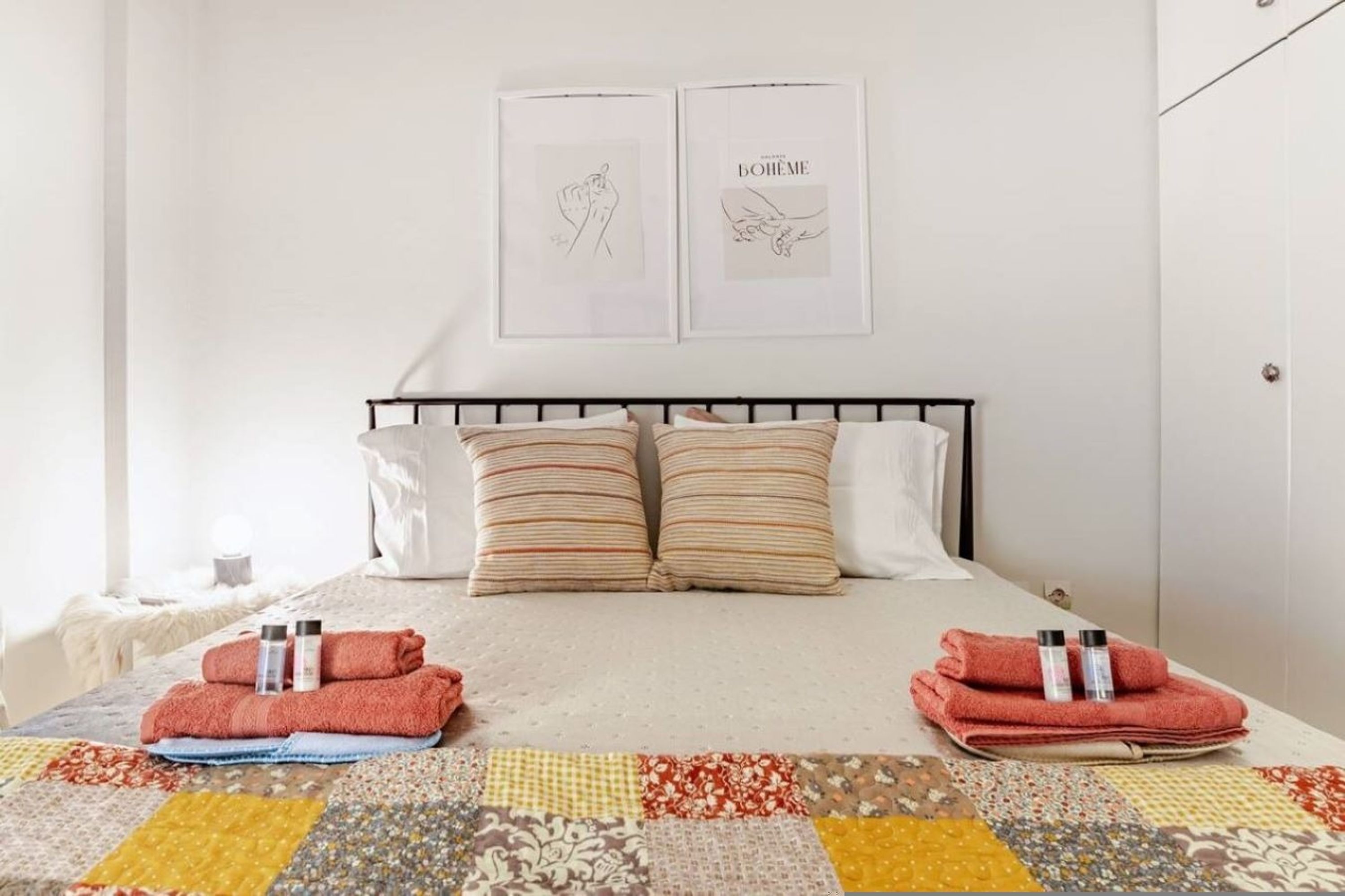 Una cama bien hecha con almohadillas a rayas, un edredón y toallas.
