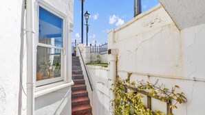 A narrow stairway leading to a white building with a window and a street lamp. - Seaside Gem Apartment By My Getaways (Brighton)