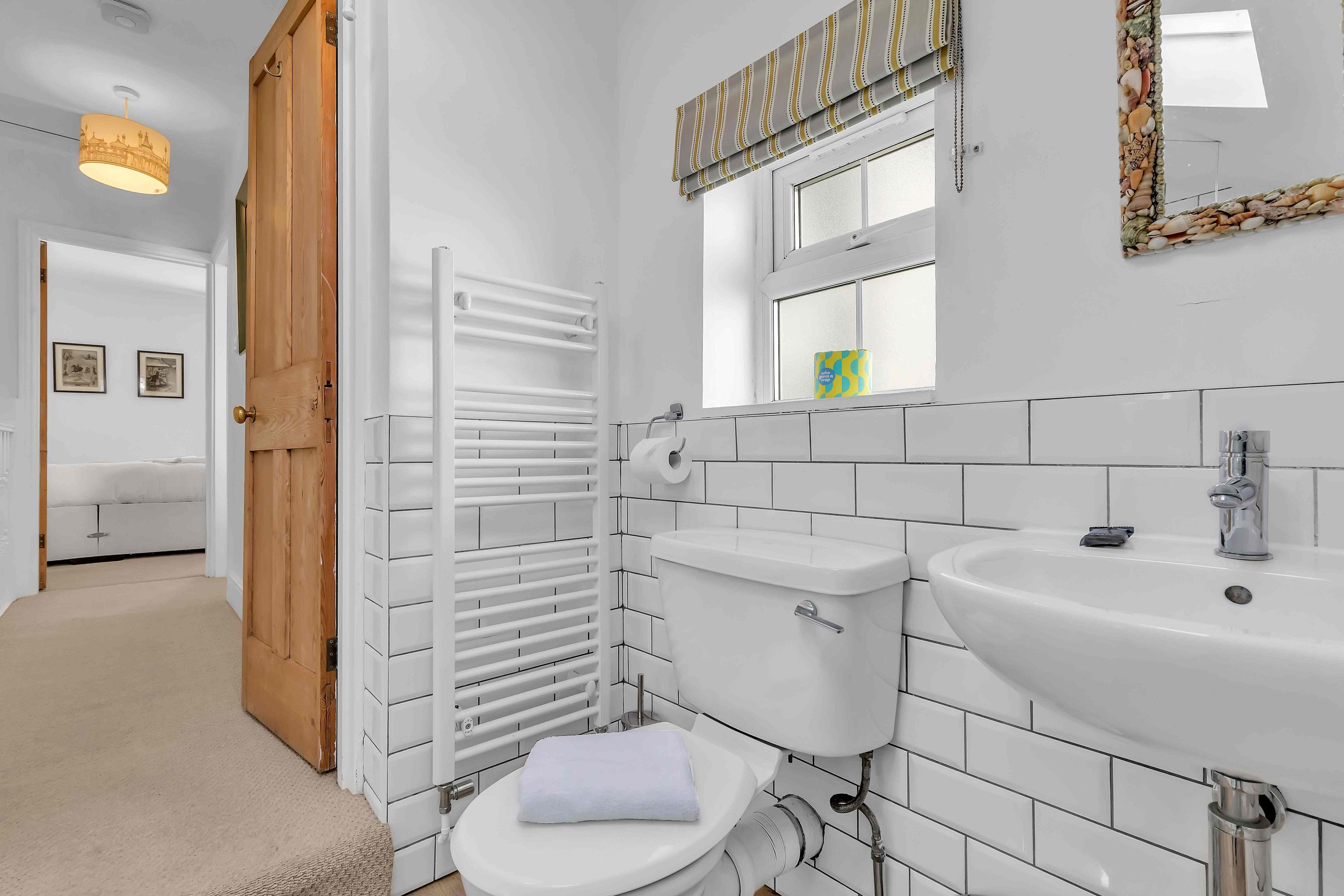 A modern bathroom with a white toilet, a sink, and a towel on the toilet.