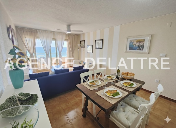 A dining area with a table set for a meal, a sofa, and a view of the sea.