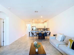 A modern living room with a sofa, coffee table, and dining area with chairs.