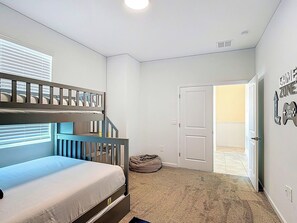 A bedroom with a bunk bed, a single bed, a door leading to a balcony, and a wall with motivational stickers. - Next to Epic Univers | Clubhouse Access Included (Davenport)