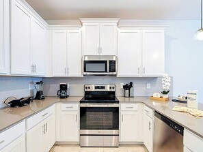 A modern kitchen with white cabinets, a stainless steel microwave, an oven, and a dishwasher. - Next to Epic Univers | Clubhouse Access Included (Davenport)