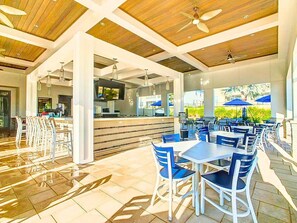 An outdoor dining area with tables and chairs, a bar area, and a view of the outdoors.