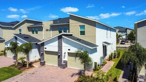 A residential complex with modern architecture, featuring multiple units with attached garages and a well-maintained landscaped driveway.