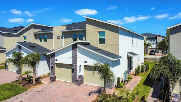 A residential complex with modern architecture, featuring multiple units with attached garages and a well-maintained landscaped driveway.