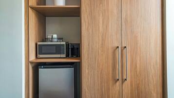 Una cocina pequeña con microondas, cafetera y refrigerador.