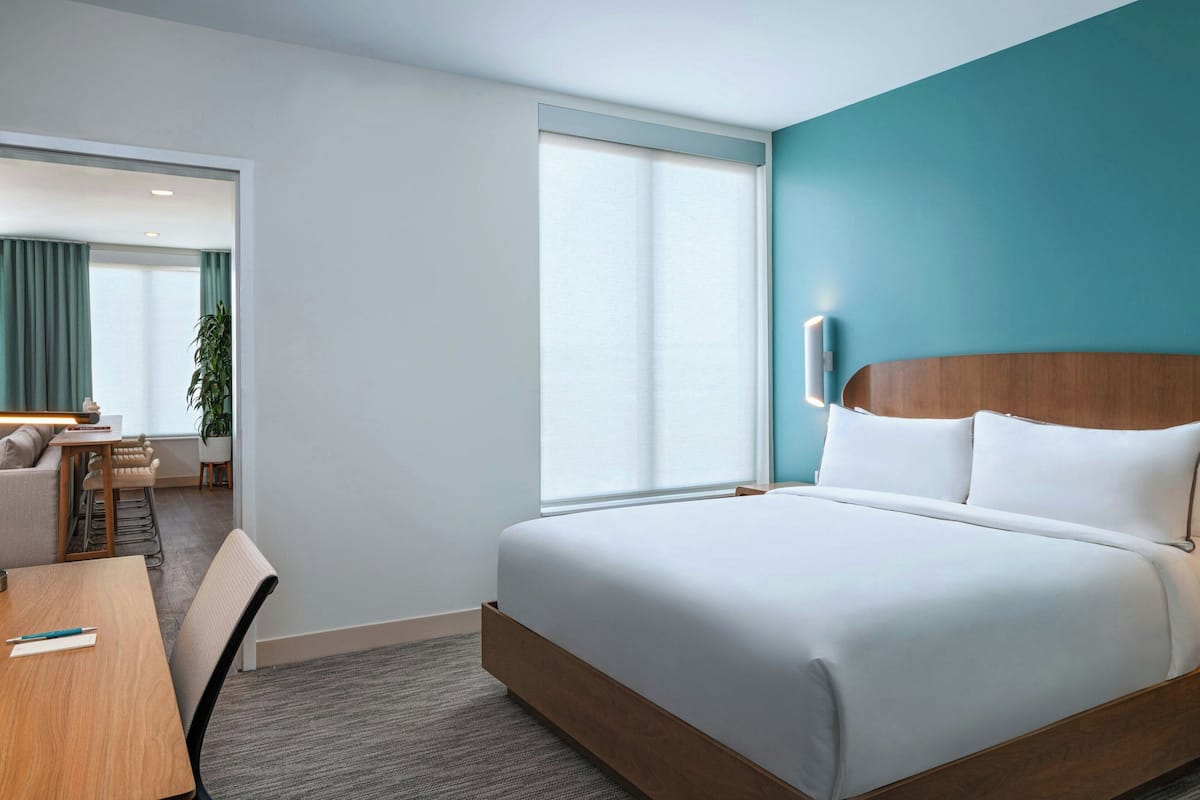 A hotel room with a bed, a desk, and a chair.