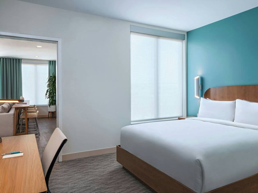 A hotel room with a bed, a desk, and a chair.