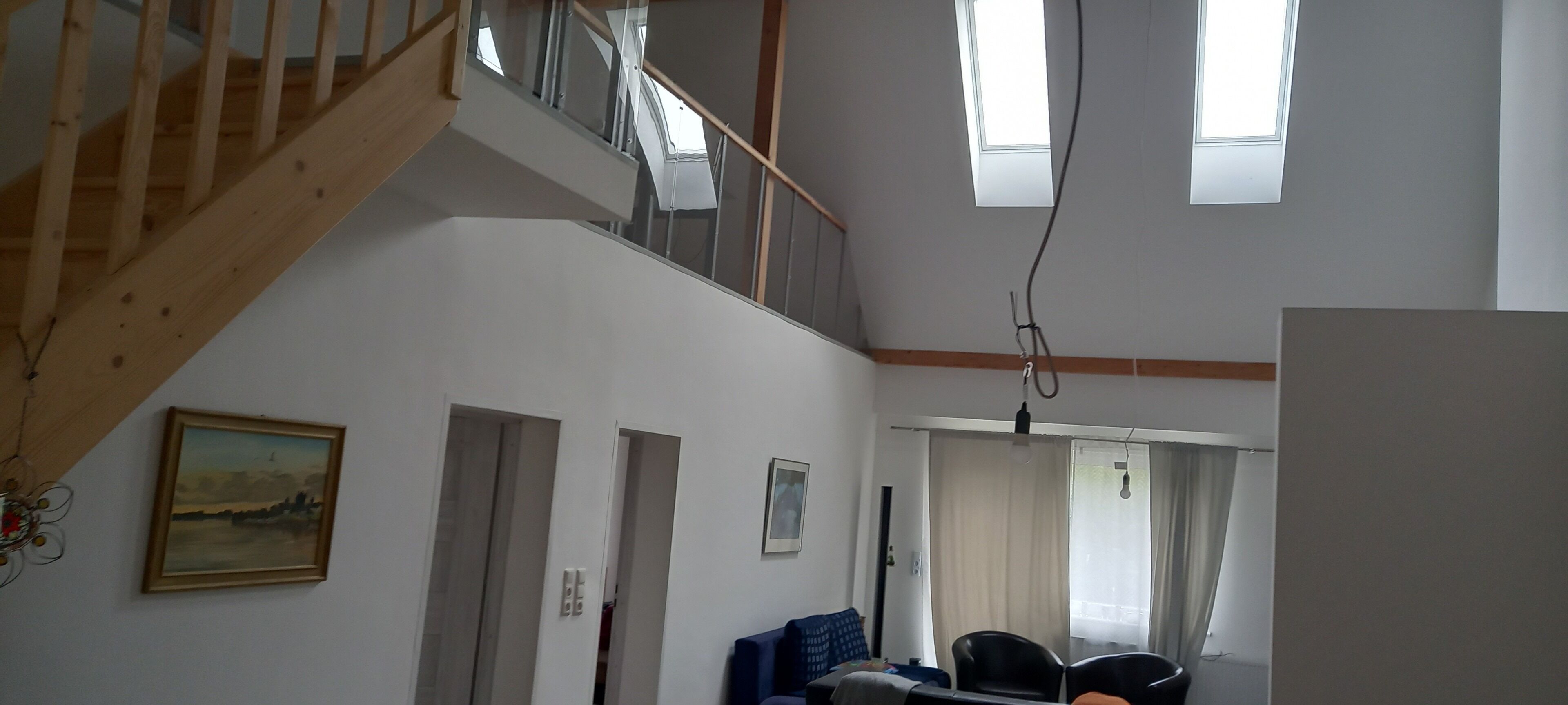 Un intérieur à plusieurs niveaux, avec un escalier, un coin repas et une vue sur l’extérieur.