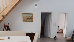 Un coin repas avec une table et des chaises, un tableau accroché au mur et un escalier.