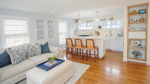 A modern kitchen with white cabinets, a central island with bar stools, and pendant lighting. - Charming 3-Bedroom Home in the Heart of Oak Bluffs (Oak Bluffs)