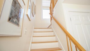 A staircase with wooden handrails and white walls, leading to a door. - Charming 3-Bedroom Home in the Heart of Oak Bluffs (Oak Bluffs)