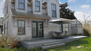A two-story house with a covered patio and a small deck. - Charming 3-Bedroom Home in the Heart of Oak Bluffs (Oak Bluffs)