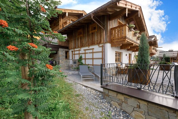 Eine Holzchalet mit Balkonen, einem Steinweg und Sitzgelegenheiten im Freien.