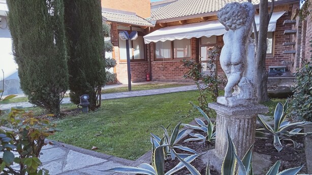 A garden with a statue, a brick house, and a well-maintained lawn. - At the home of "Nuccia" (Foglizzo)