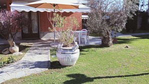A well-maintained garden with a patio area, a large decorative planter, and a white umbrella. - At the home of "Nuccia" (Foglizzo)