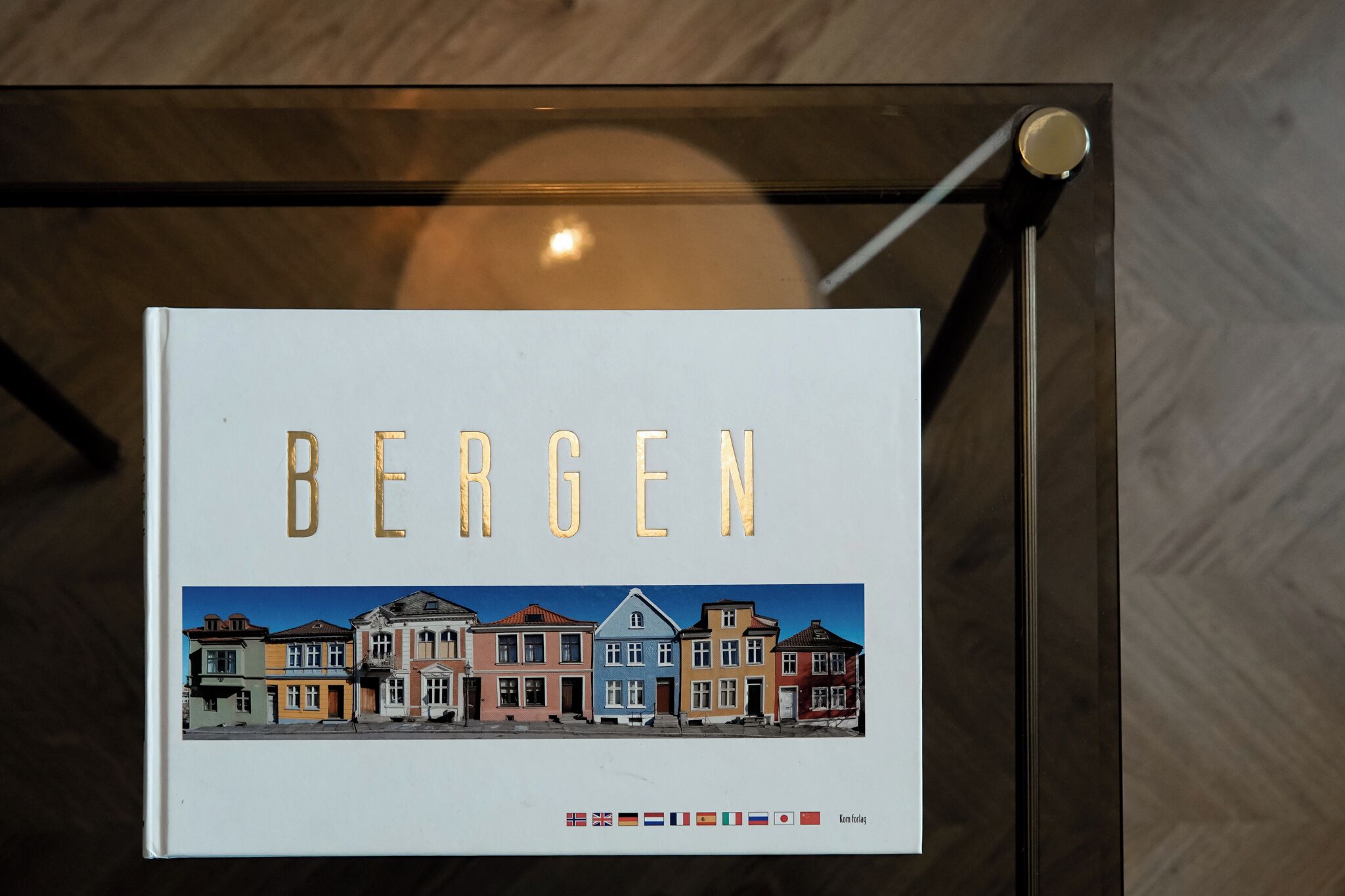 En inramad bild av en gata med färgglada byggnader och ordet ”BERGEN” skrivet med gyllene bokstäver.